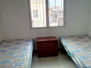 Zona de dormitorio con dos camas y mesita